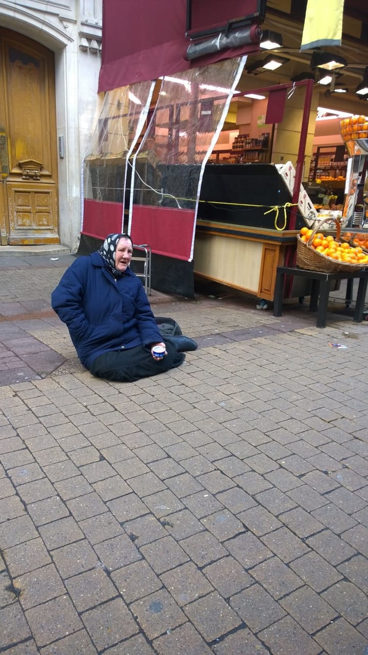 Mulher sentada na calçada, no chão, pedindo esmola - retrato da pobreza e vulnerabilidade feminina