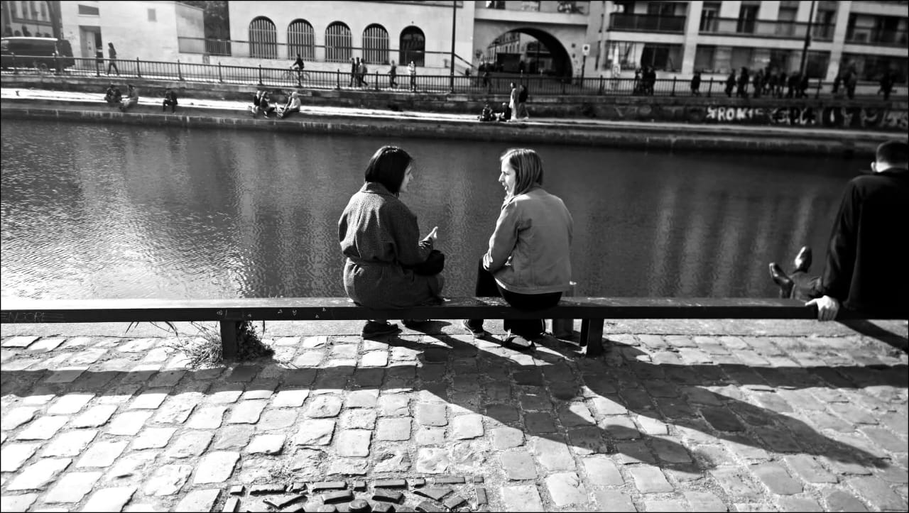 Mulher muçulmana sentada em um banco, conversando com mulher ocidental - diálogo entre culturas
